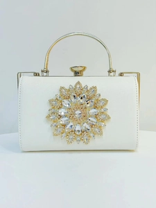 Detailed view of the sparkling sunburst crystal flower on white evening clutch bag