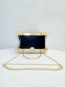 Detailed view of the gold evening bag featuring its black lining and metal frame detail