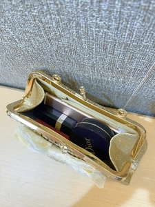 Dettaglio interno della borsa da sera dorata con spazio per smartphone e rossetto