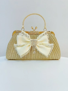 Dettaglio pochette dorata con fiocco di raso bordi in pizzo e nappa di strass