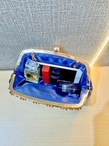 Detail showing inner capacity of blue sequin evening clutch with smartphone and makeup
