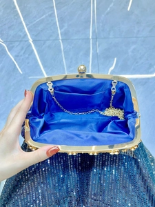 Deep blue sequin clutch bag with gold metal frame shown open with chain strap