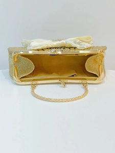 Dettaglio dell'interno della borsa da sera con paillettes dorate, fiocco in raso e pizzo