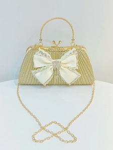 Dettaglio della borsa da sera con paillettes dorate, fiocco in raso bianco e strass