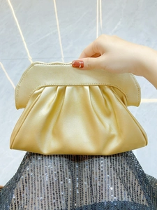 Detailed view of the champagne gold shell-pleated evening clutch with metallic finish