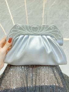 Detail of silver evening clutch bag with pearl and rhinestone wavy top frame decoration