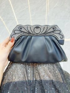 Detail of black pleated clutch with intricate rhinestone scrollwork on metal frame