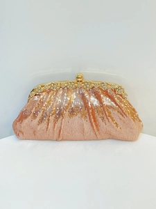 Detailed shot of sparkling champagne sequins and floral rhinestone clasp on evening clutch