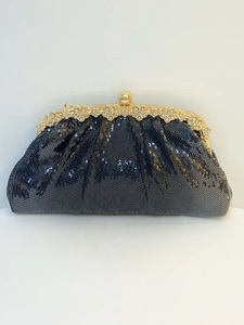 Detail of black sequined evening clutch bag with gold flower clasp and rhinestone accent