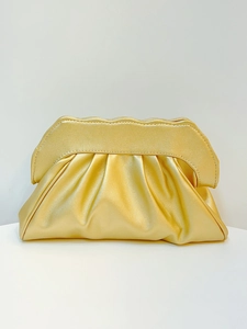 Detail of golden pleated cloud clutch bag with unique wavy metal frame closure