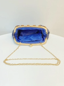 Macro shot of dark blue sequined evening bag interior with blue satin lining and gold chain