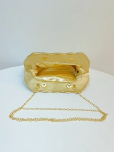 Detail of champagne gold evening bag showing magnetic closure and golden chain strap