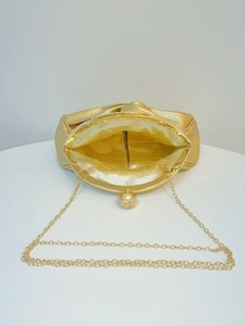 Inside view of gold satin evening clutch featuring chain strap and pearl diamond clasp