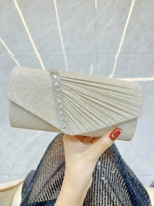 Detail of champagne gold evening clutch with pleated fabric and sparkling rhinestones