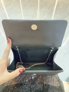 Sparkly black evening clutch bag with silver chain strap and magnetic closure shown open