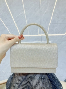 Detailed close-up of champagne gold glitter evening bag with semi-circular handle