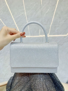 Close-up of silver glitter evening clutch bag with curved handle and magnetic flap