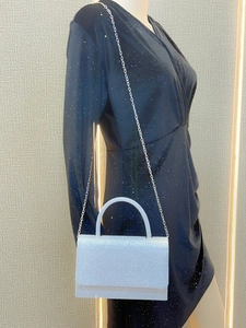 Close-up of white glitter evening clutch bag with silver chain and rigid top handle