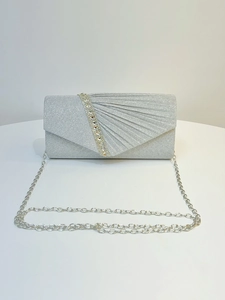 Detailed macro shot of silver evening clutch bag with pleated fabric and rhinestone strap