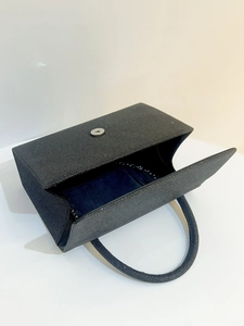 Detail of black glitter evening handbag featuring rectangular shape and magnetic closure
