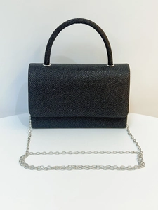 Detail of black glitter evening bag with silver metal chain and glossy top handle