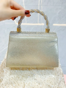 Detail of the champagne gold clutch bag featuring a crystal-encrusted twisted handle