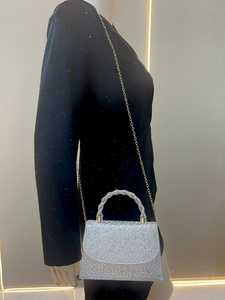 Detail of silver rhinestone evening bag featuring a unique twisted metal handle and chain