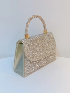 Macro view of luxurious rhinestone clutch featuring crystal rope handle and metal clasp