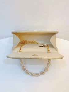Detail of champagne gold evening bag with rhinestones, interior lining and chain strap