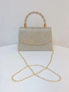 Detail of gold rhinestone evening bag featuring twisted metal handle and fine chain strap