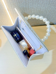 Internal view of a crystal clutch showing storage for phone, perfume and cosmetics