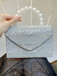 Detailed view of the luxury evening bag featuring sparkling rhinestones and a large pearl handle