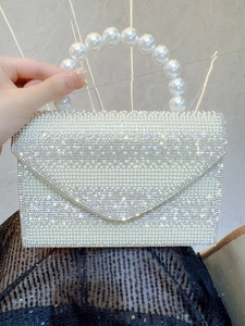 Macro shot of faux pearl handle and sparkling rhinestones on the bridal clutch