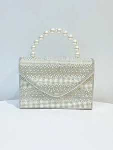 Detail of evening bag with faux pearls and rhinestones on wave-shaped flap