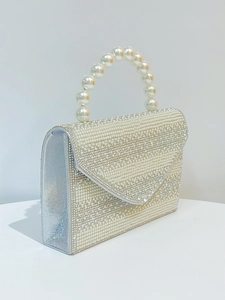 Close-up of elegant silver evening bag featuring dense pearls and shimmering rhinestones