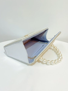 Detail of white pearl evening bag showing light blue lining and gold chain strap