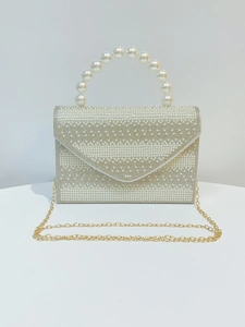 Close-up of pearl evening clutch with shimmering rhinestones and a beaded top handle