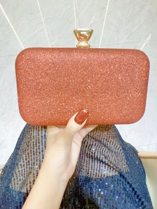 Close-up of coral orange glitter evening clutch bag with elegant gold metal clasp