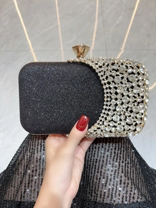 Detailed close-up of a luxury black evening clutch with sparkling rhinestones and gold trim