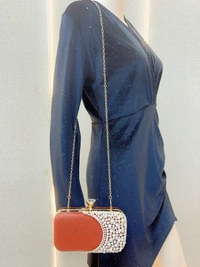 Detailed view of red glitter evening clutch bag with sparkling rhinestones and gold chain