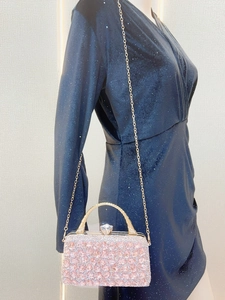 Detail of pink and silver rhinestone evening bag with gold handle on glitter dress