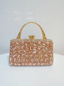Detail of peach pink rhinestones and gold bamboo-shaped handle on luxury evening clutch