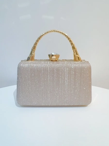 Close-up of champagne gold evening bag featuring sparkling glitter and a rhinestone clasp
