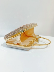 Detail of evening clutch with sparkling crystals, gold handle and champagne satin lining