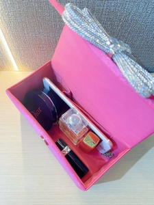 Interior view of pink silk clutch bag showing space for phone, perfume and cosmetics