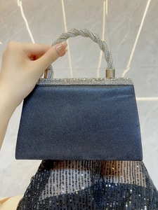 Detail of navy blue evening clutch featuring a twisted silver rhinestone handle and clasp
