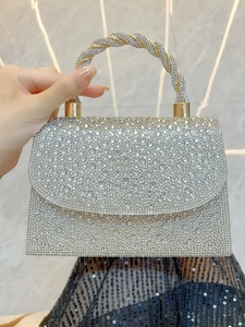 Close-up of sparkling silver rhinestone evening clutch with textured gold handle