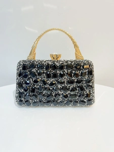 Macro detail of black crystal evening bag with golden handle and diamond clasp