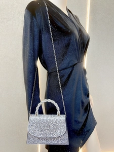 Detail of silver rhinestone evening bag featuring twisted handle and metallic chain strap
