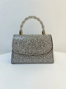Detailed macro view of the sparkling rhinestone surface and braided handle of the evening bag